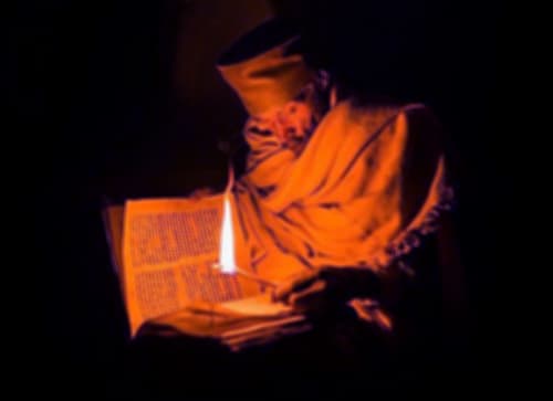 تحتوي الصورة على رجل و شمعه و كتاب 
عمل سحر للحبيب 